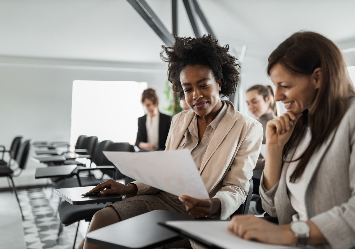 Woman of color working alongside white woman in an office setting discussing inclusive design principles