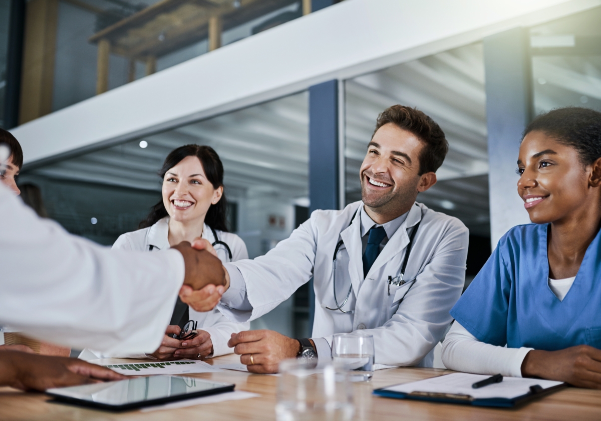 A diverse team of job recruiters who have implemented diversity hiring shake the hand of a new hire.