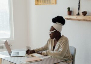 Beautiful Black woman with braids wears a robe while sitting at her desk in her home office happy with her company's diversity recruiting strategy