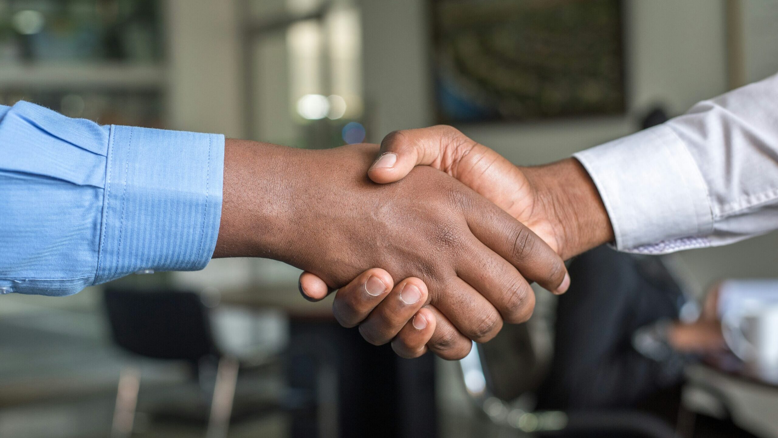 Two Black employees shake hands. recruiting strategies African American community members.